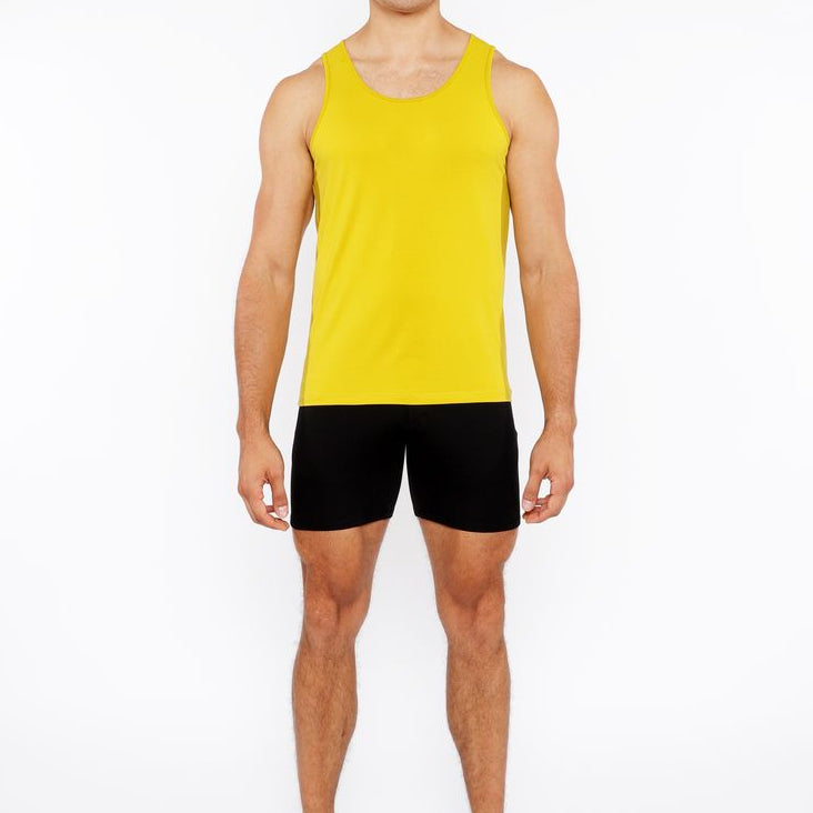 Man wearing a yellow tank top and black shorts on a white background