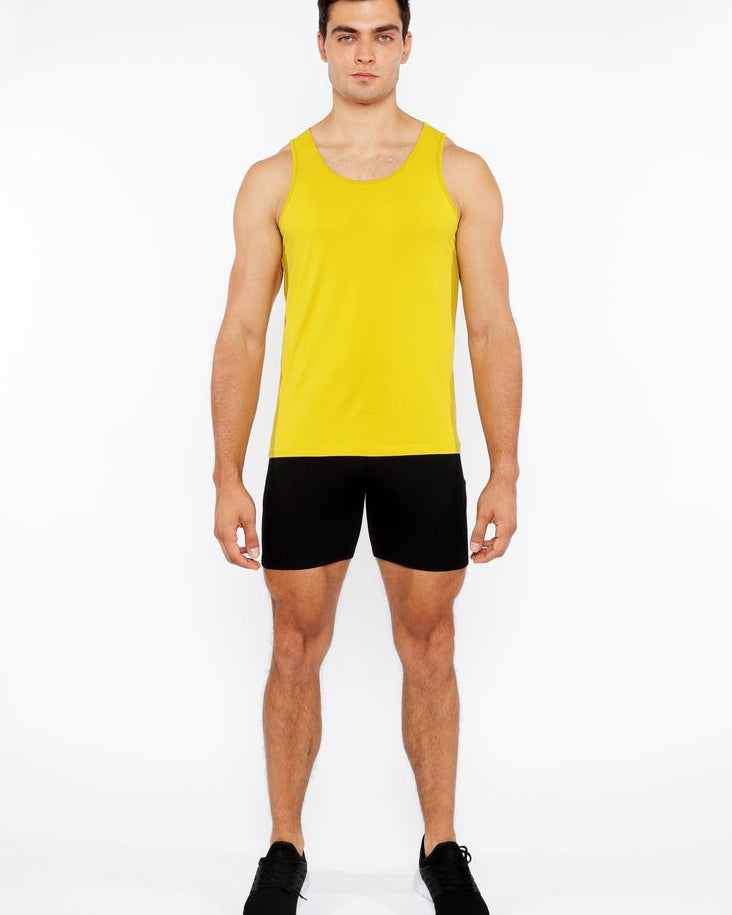 Man wearing a yellow tank top and black shorts on a white background