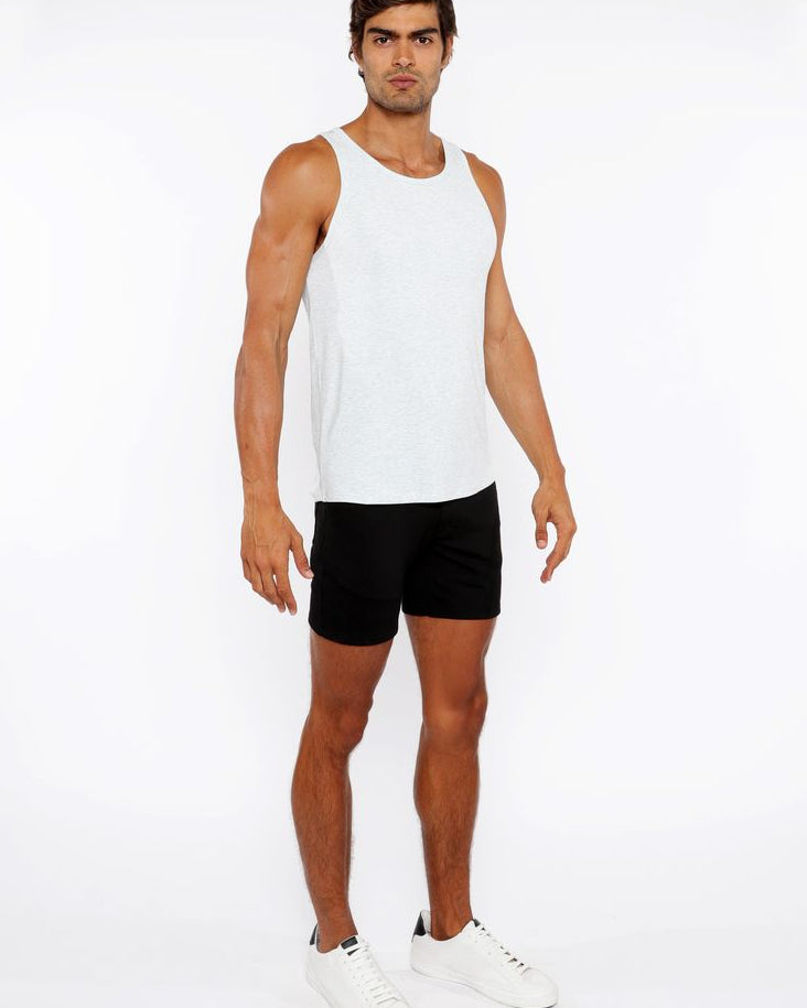 Man wearing a white tank top and black shorts on a white background