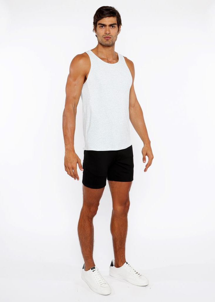 Man wearing a white tank top and black shorts on a white background