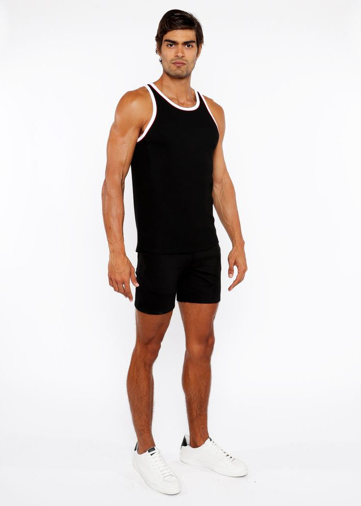 Man wearing a black tank top and shorts on a white background