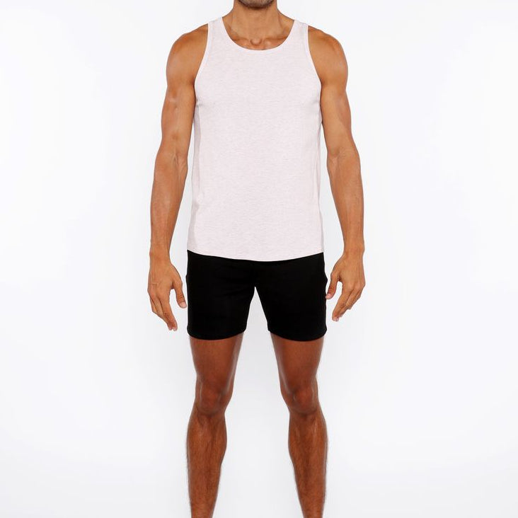 Man wearing a white tank top and black shorts on a white background