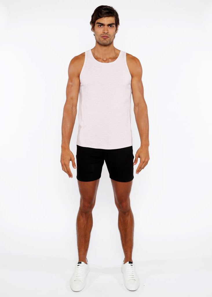 Man wearing a white tank top and black shorts on a white background