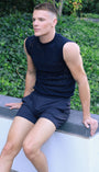 Man sitting on a concrete ledge with greenery in the background