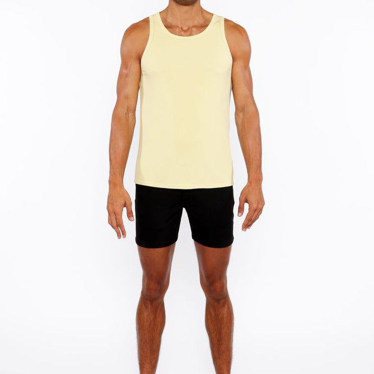 Man wearing a yellow tank top and black shorts on a white background