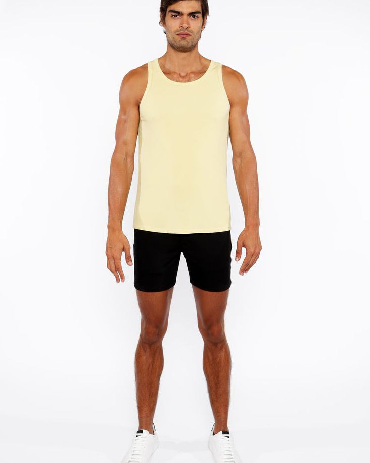 Man wearing a yellow tank top and black shorts on a white background