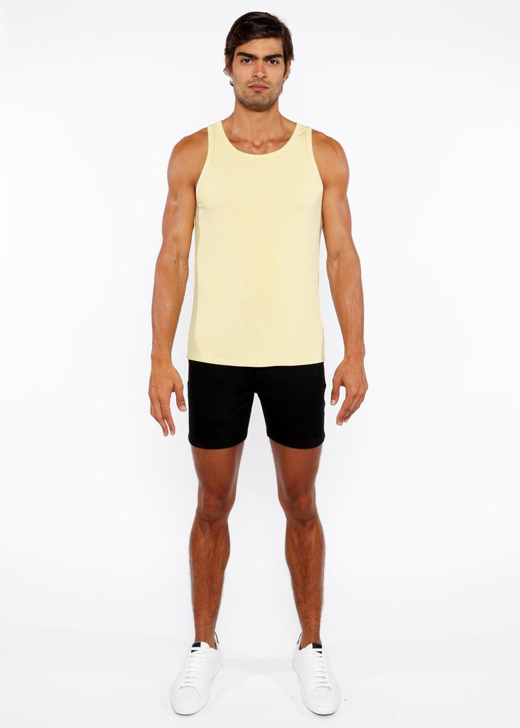 Man wearing a yellow tank top and black shorts on a white background