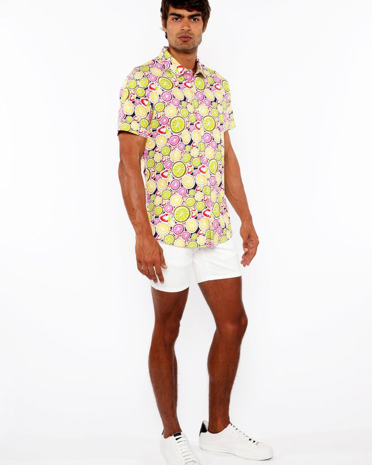 Man wearing a colorful floral shirt and white shorts on a white background