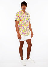 Man wearing a colorful floral shirt and white shorts on a white background