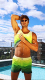 Man in colorful swimwear posing by a pool with a cityscape in the background