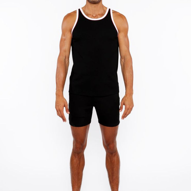 Man wearing a black tank top and shorts on a white background