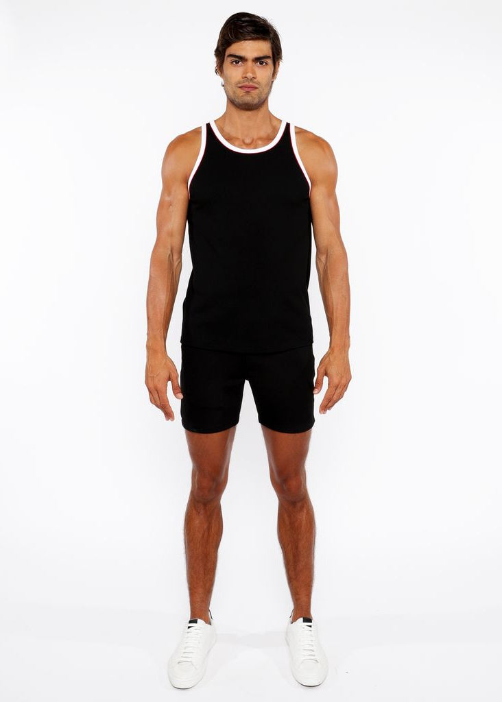 Man wearing a black tank top and shorts on a white background