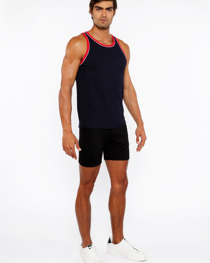 Man wearing a black tank top with red trim and black shorts on a white background