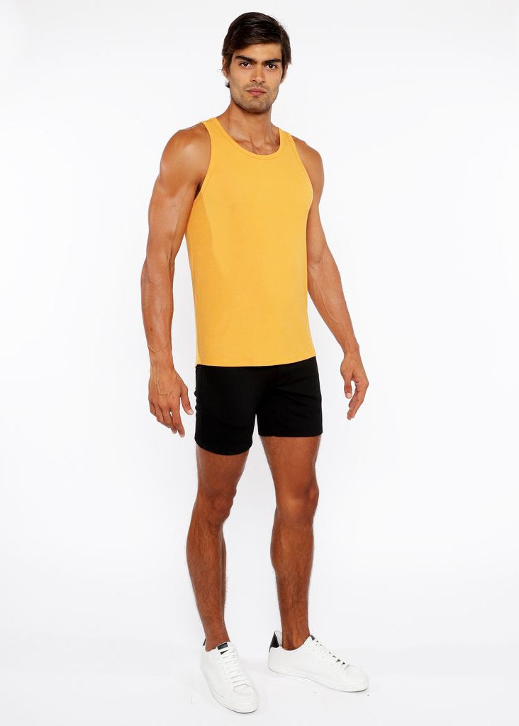 Man wearing a yellow tank top and black shorts on a white background