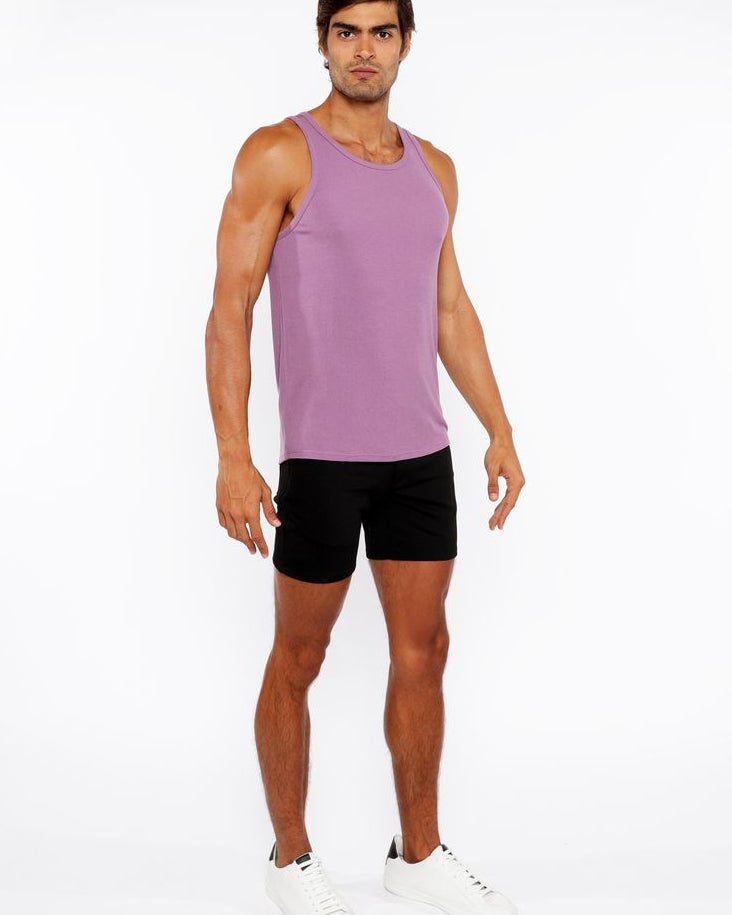 Man wearing a purple tank top and black shorts on a white background